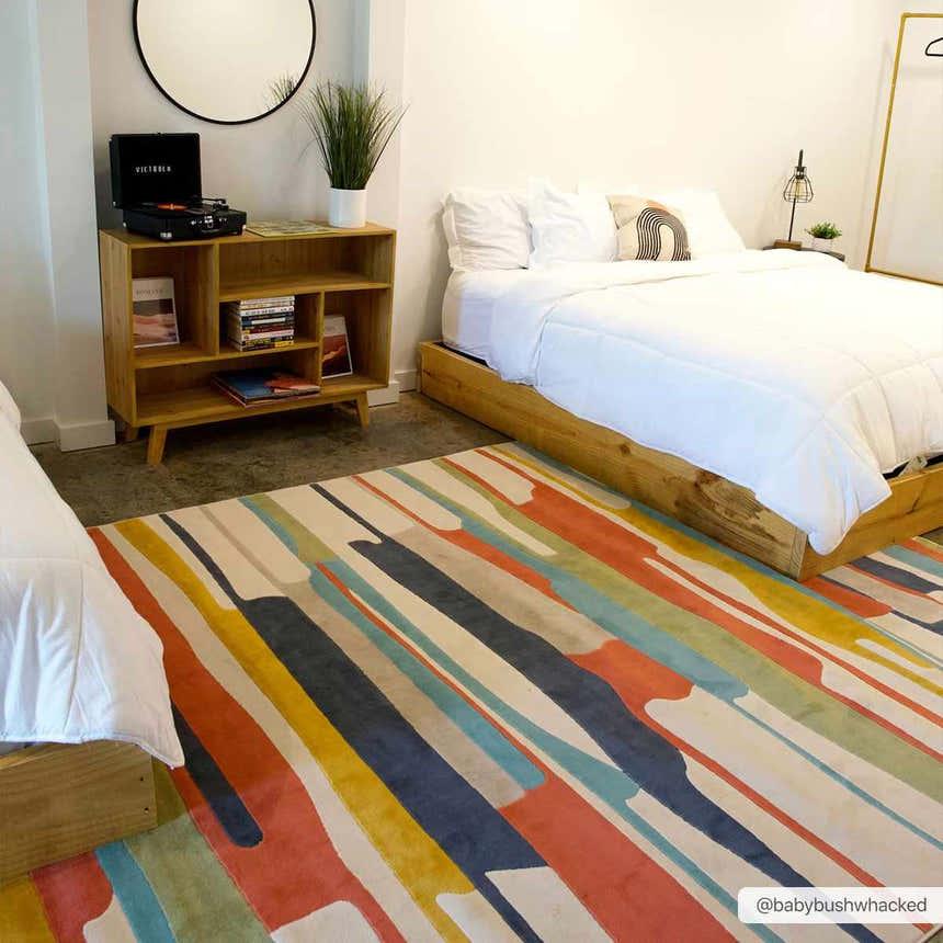 Bedroom scene with a colorful Southfields rug, wood bed frames, and mid-century modern decor. Roomscene-Rectangle