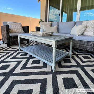 Outdoor patio scene with gray wicker furniture and the Spilsby Geometric Outdoor Rug in black and light beige. Roomscene-Rectangle
