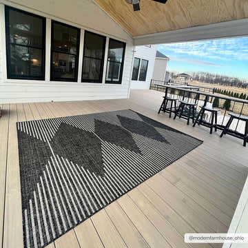 Modern farmhouse porch with black Stephan Area Rug, bar-height table and stools, and white siding. Roomscene-Rectangle