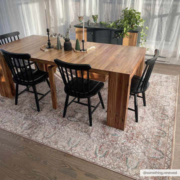 Dining room scene with a wood table and black chairs on a Suay Area Rug in charcoal, cream, and dusty pink. Roomscene-Rectangle