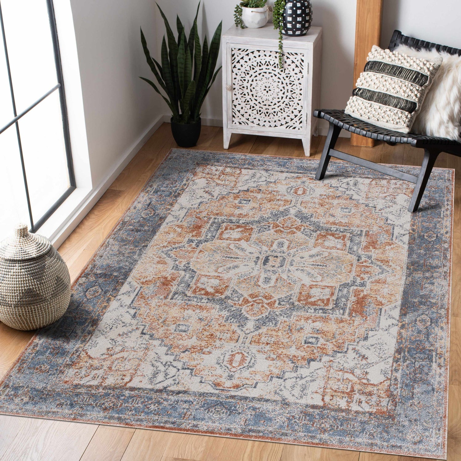 Living room scene with a blue and orange Hera Washable area rug, black chair, and white cabinet. Traditional vintage style. Roomscene-Rectangle