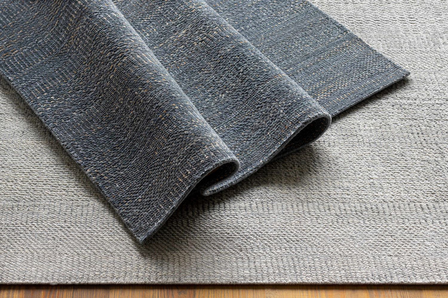 Close-up of the hand-knotted Hoole Area Rug. Features dark blue, denim, and off-white wool textures. Contemporary style. Styleshot