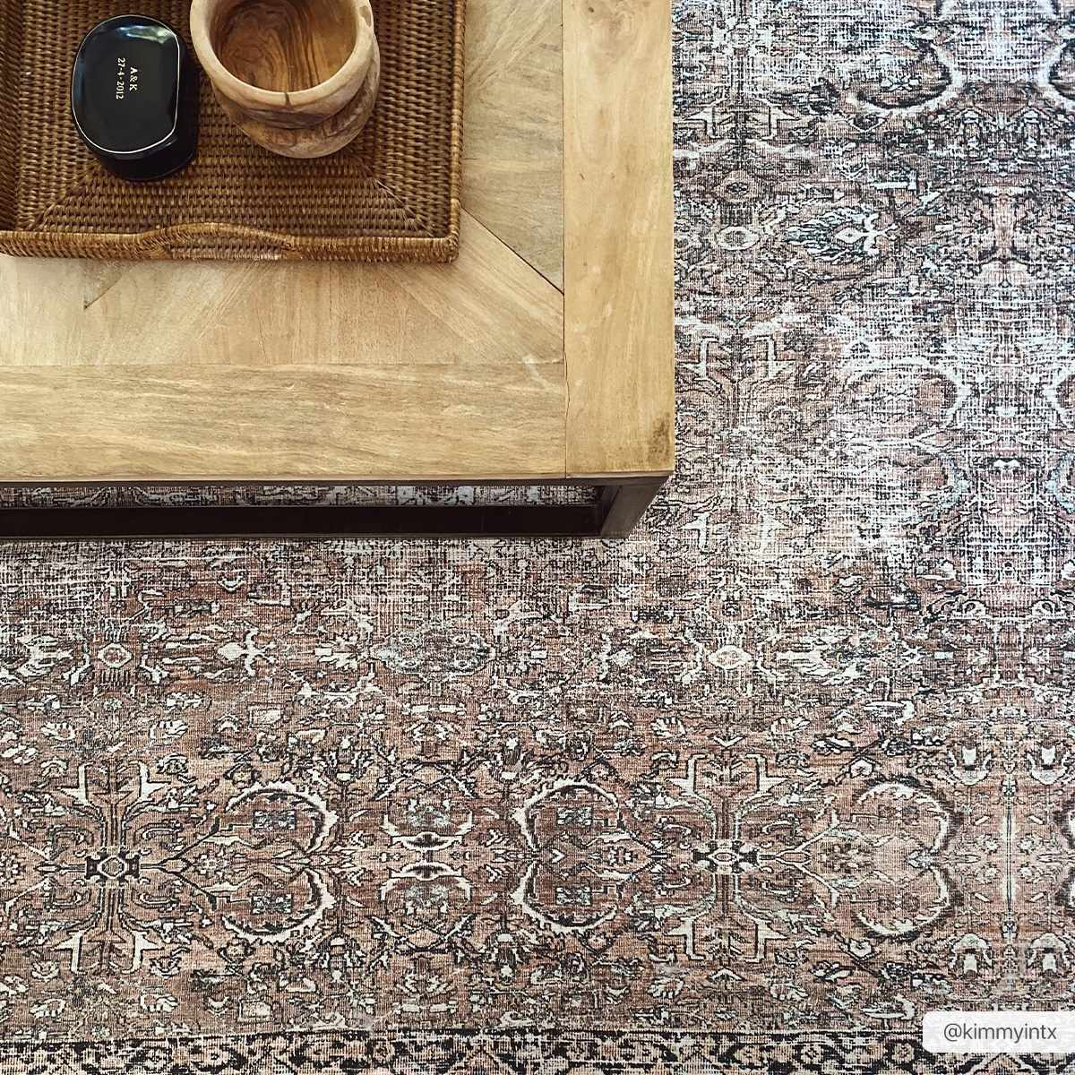 Close-up of a Jill Washable Area Rug in brown and blue with a vintage Persian-style pattern under a light wood coffee table. Styleshot
