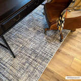Home office scene with a Taysan area rug in dark gray and taupe under a desk and leather chair. Roomscene-Rectangle