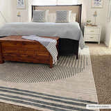 Bedroom scene with a Thad Medium Gray Washable Area Rug, wood chest, gray bedding, and white nightstand. Modern, cozy style. Roomscene-Rectangle