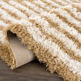 Close up of a Calup Shag Area Rug showing the bone and dark brown striped pattern and plush texture. Fold