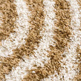 Close-up of the Calup Shag Area Rug showing its bone and dark brown geometric pattern and plush, shaggy texture. Texture