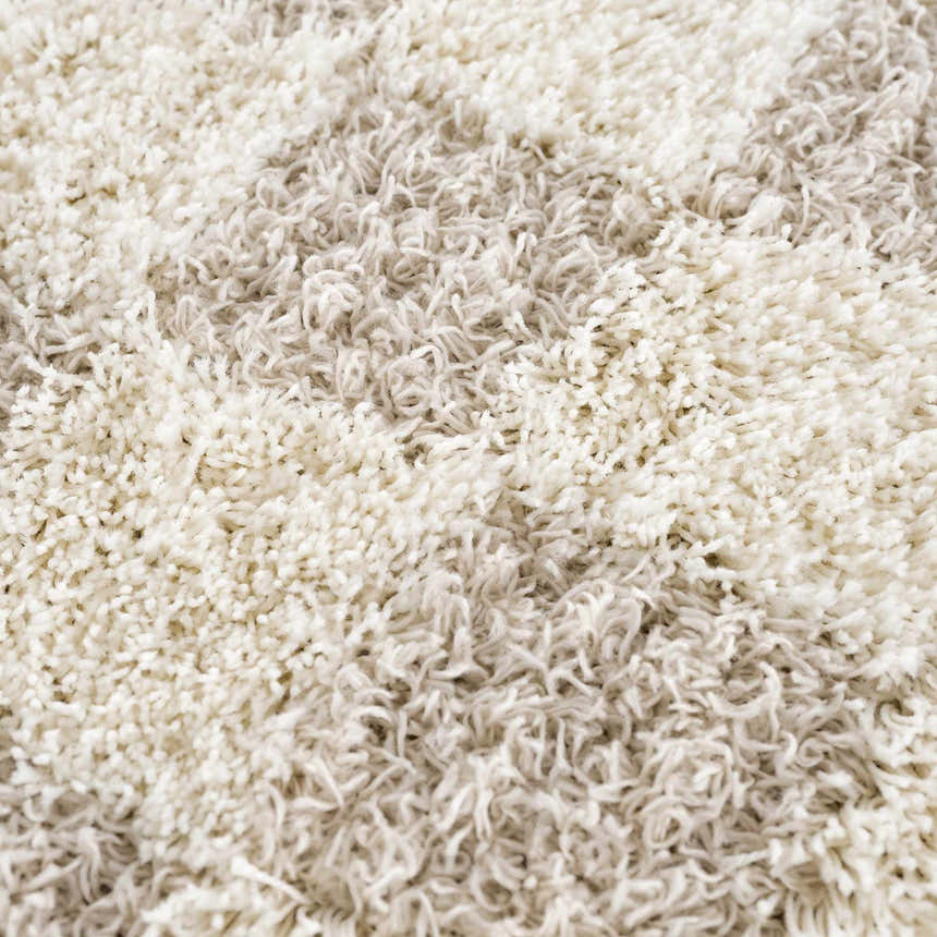 Close-up of the shaggy Atira Light Brown Checkered Area Rug, showing cream and light beige fibers. Texture