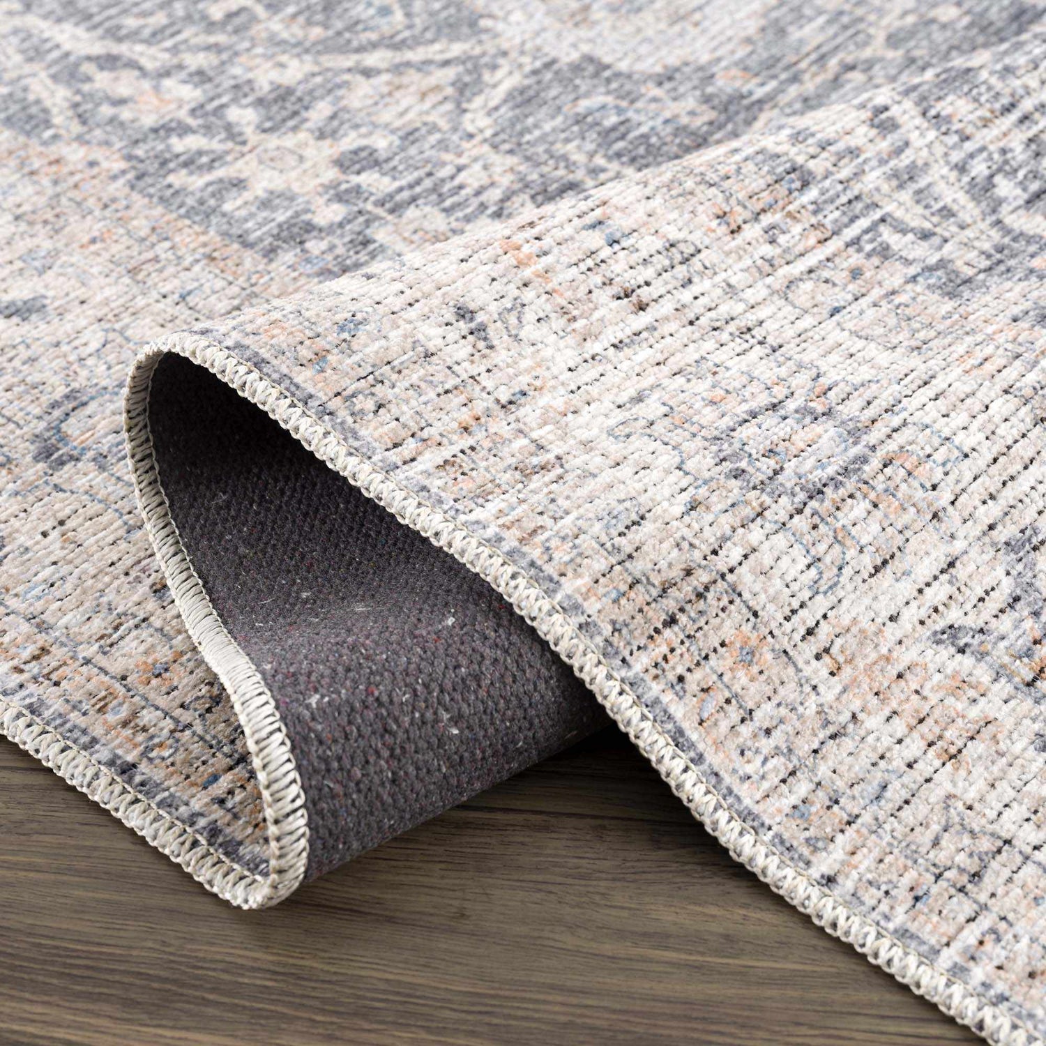 Close-up of the Kayin Washable Rug showing its silver and gray traditional pattern and chenille-polyester texture. Fold
