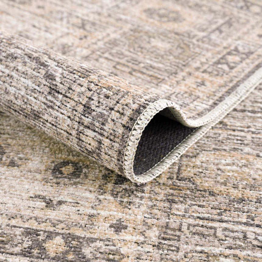 Close up of the Keola Washable Area Rug showing its texture, neutral colors, and traditional pattern. Fold