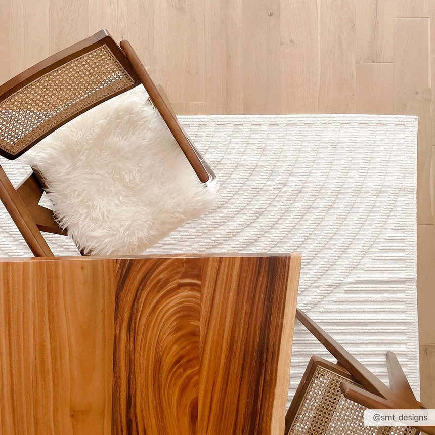 Top-down shot of the Deron White Washable 3D Rug styled with a wood table and chair on a light wood floor. Styleshot