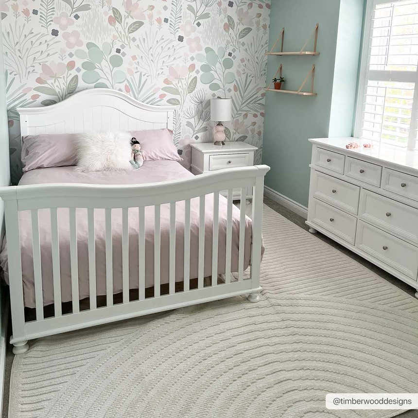 Nursery with white furniture and floral wallpaper featuring the Deron White Washable 3D Rug. Roomscene-Rectangle