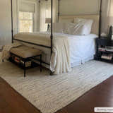 Bedroom scene with a cream and black Williford Wool Area Rug under a four-poster bed on dark hardwood floors. Roomscene-Rectangle