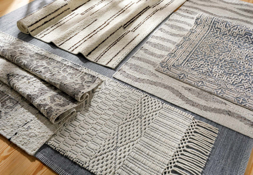 Close-up of Limoges Area Carpet Clearance rugs in black, cream, and gray with geometric, striped, and woven patterns. Styleshot