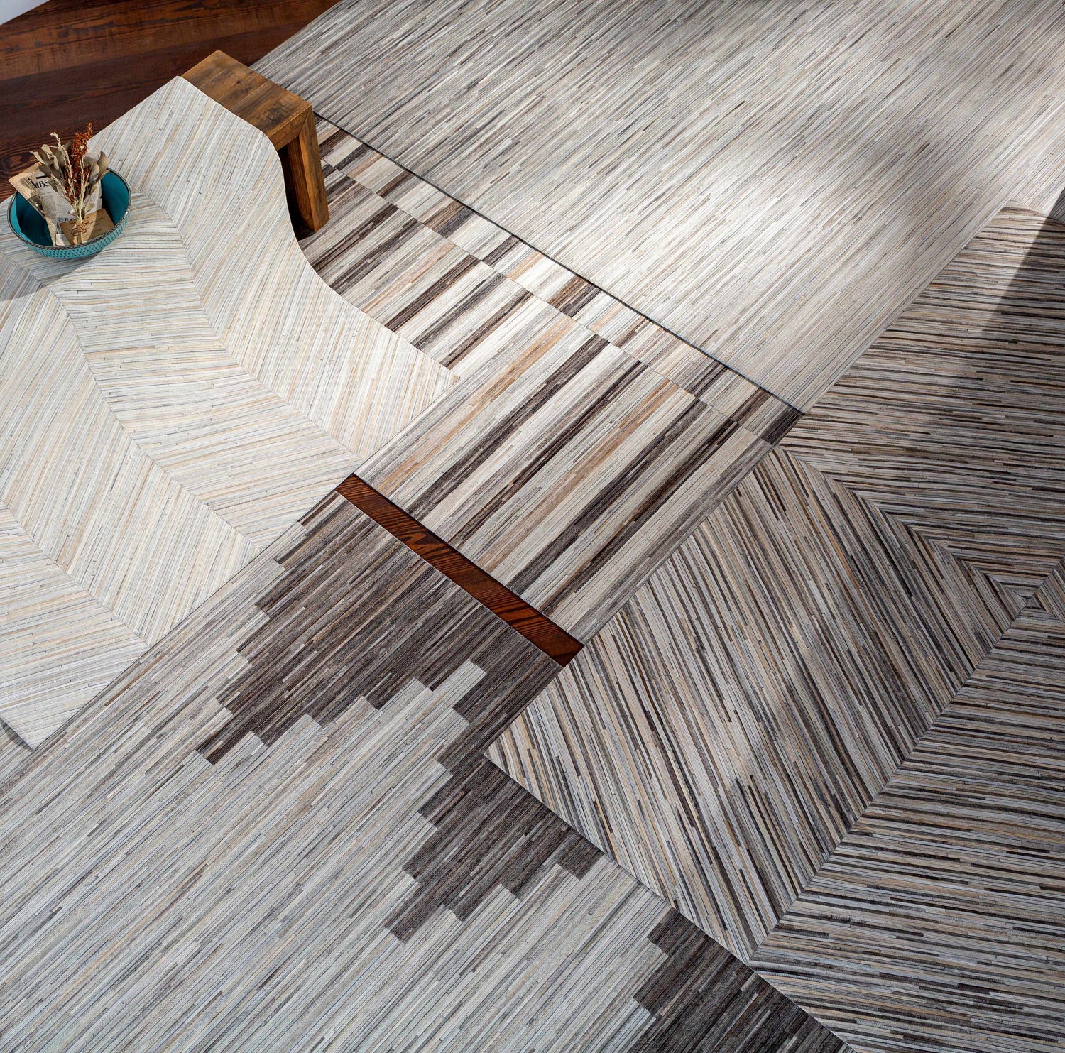 Close-up of the Shearwater Premium Rug. Hand-crafted hair-on-hide rug in beige, charcoal, and gray with a geometric pattern. Styleshot
