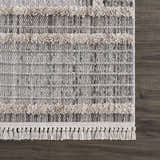 Close-up of the Amaga High-Low Rustic Rug showing the geometric pattern, cream shag stripes, and tassel fringe detail. Swatch