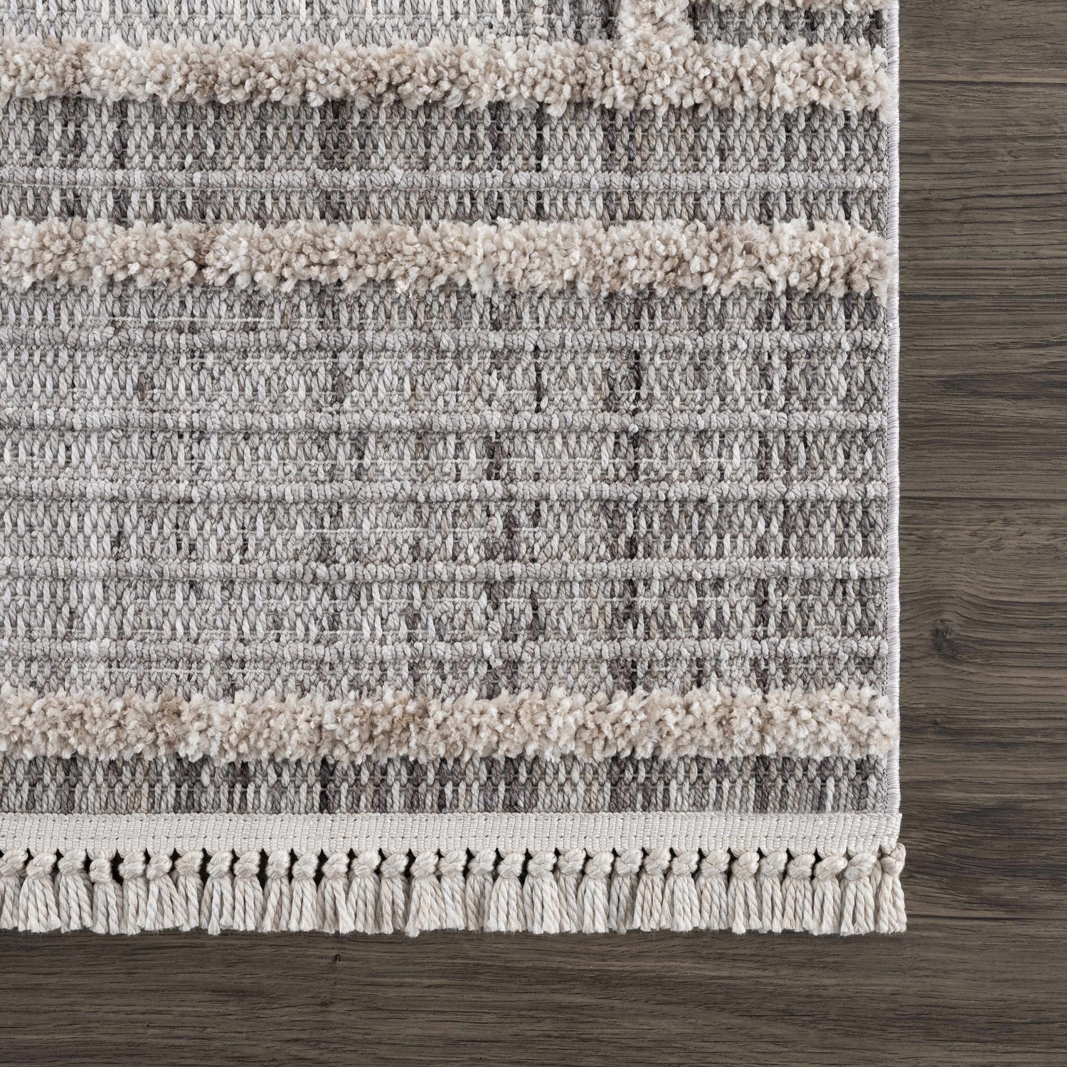 Close-up of the Amaga High-Low Rustic Rug showing the geometric pattern, cream shag stripes, and tassel fringe detail. Swatch