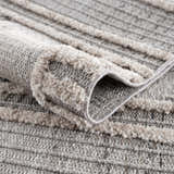 Close-up of the Amaga High-Low Rustic Rug, showing its charcoal, cream, and gray geometric pattern and textured, high-low pile. Fold