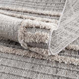 Close up of the Amaga High-Low Rustic Rug showing texture and pattern in cream, light beige, charcoal, and gray. Fold