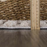 Close-up of the Amaga High-Low Rustic Rug showing its cream geometric design, texture, and pile height with a ruler. Pile