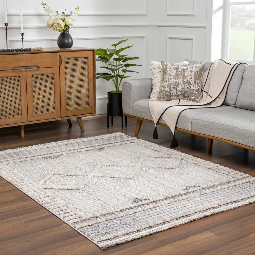 Living room scene with a gray sofa and the Amaga High-Low Rustic Rug in charcoal, cream, and beige. Roomscene-Rectangle