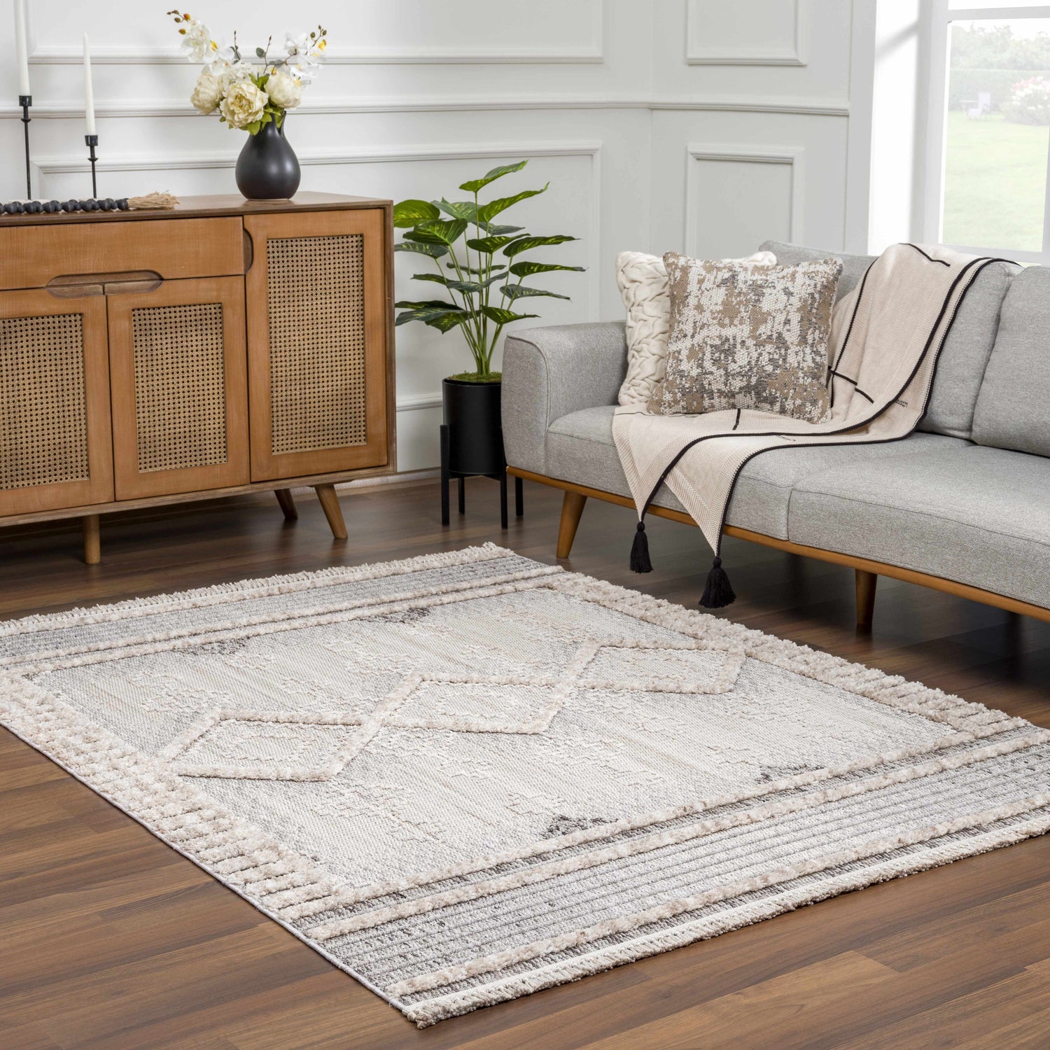 Living room scene with a gray sofa and the Amaga High-Low Rustic Rug in charcoal, cream, and beige. Roomscene-Rectangle