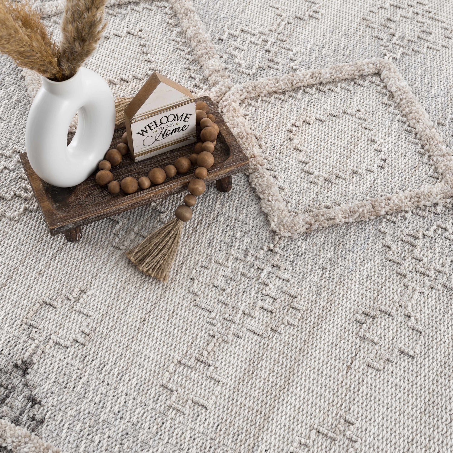Close-up of the Amaga High-Low Rustic Rug. Features a geometric pattern with charcoal, cream, and light beige tones. Styleshot