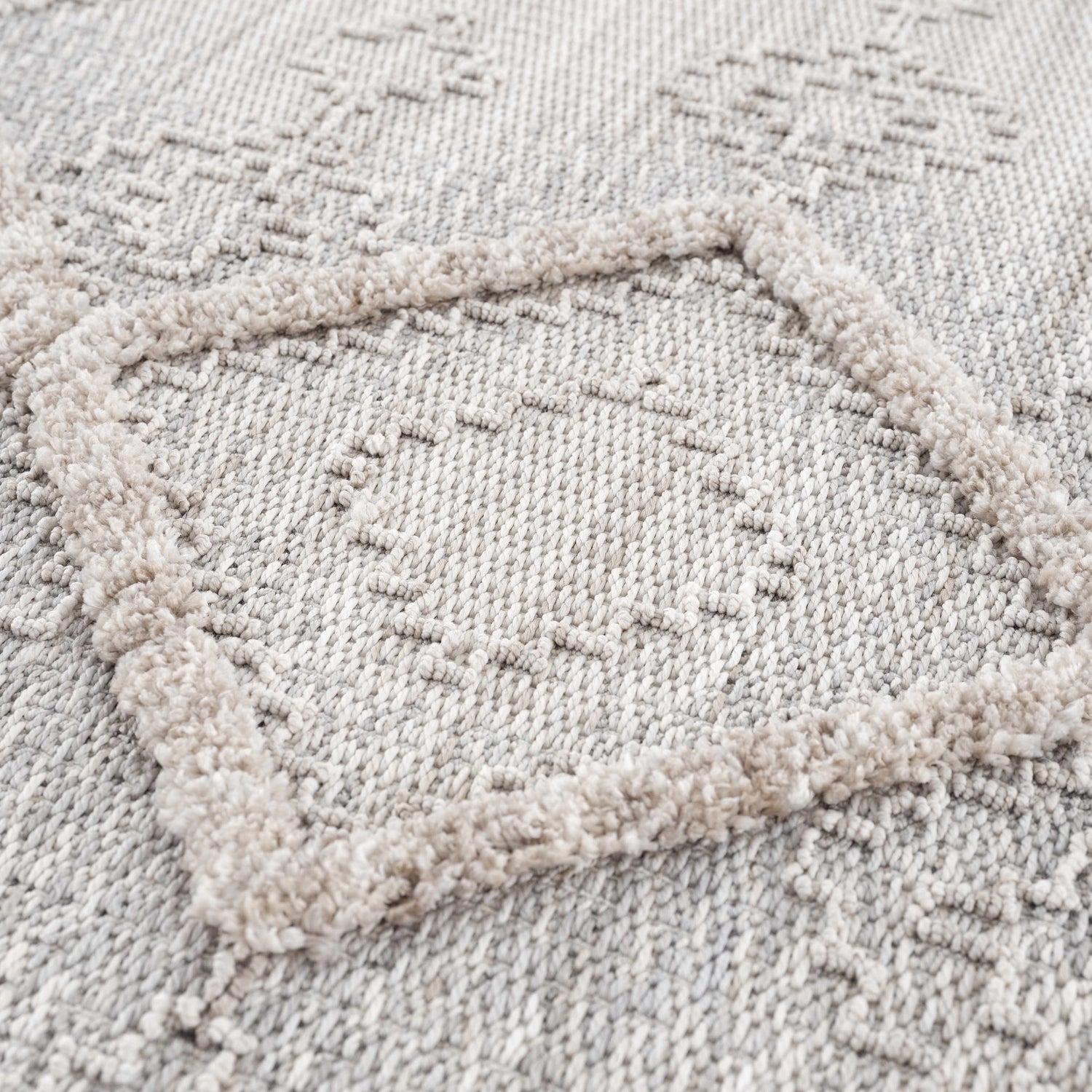 Close up of the Amaga High-Low Rustic Rug. Cream, light beige, and gray geometric pattern with high-low texture. Texture