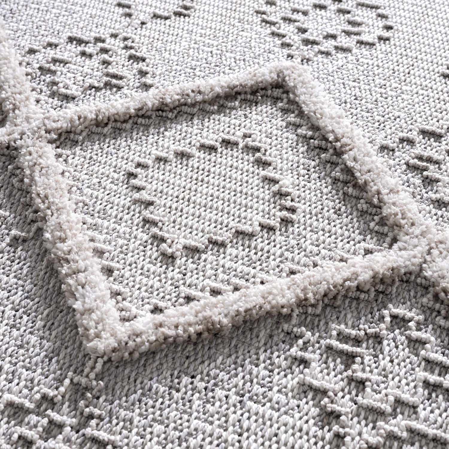 Close-up of the Amaga High-Low Rustic Rug showcasing its geometric pattern and high-low texture in charcoal and cream. Texture