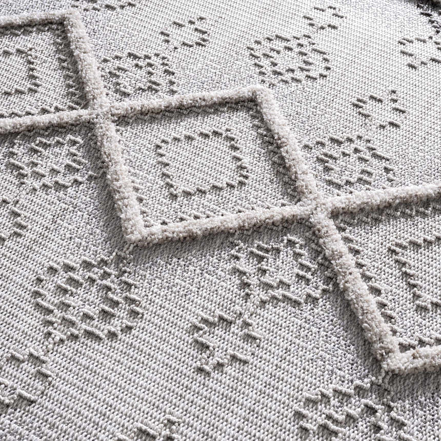 Close-up of the Amaga High-Low Rustic Rug showing its geometric pattern, high-low texture, and shades of gray and cream. Texture