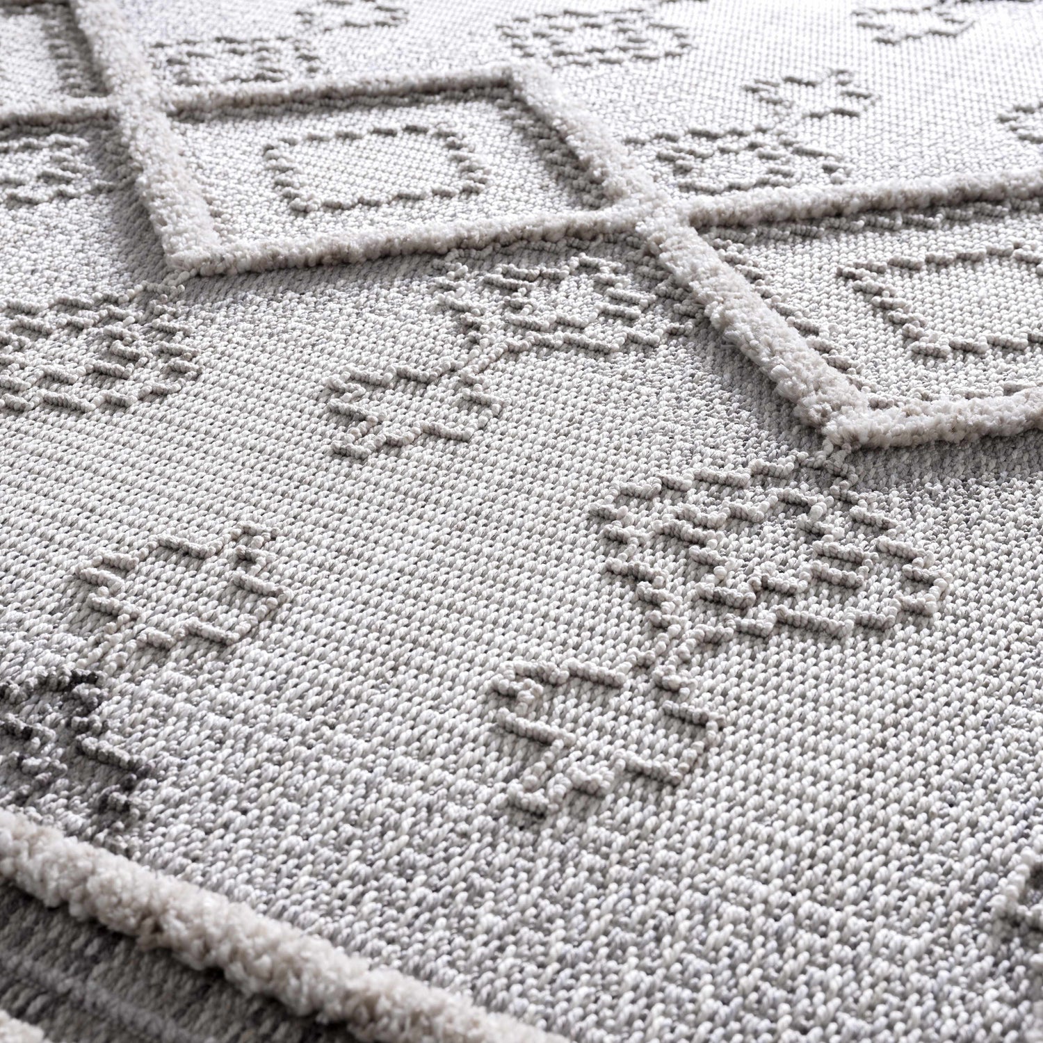 Close-up of the Amaga High-Low Rustic Rug showing its geometric design, plush texture, and charcoal and cream color palette. Texture