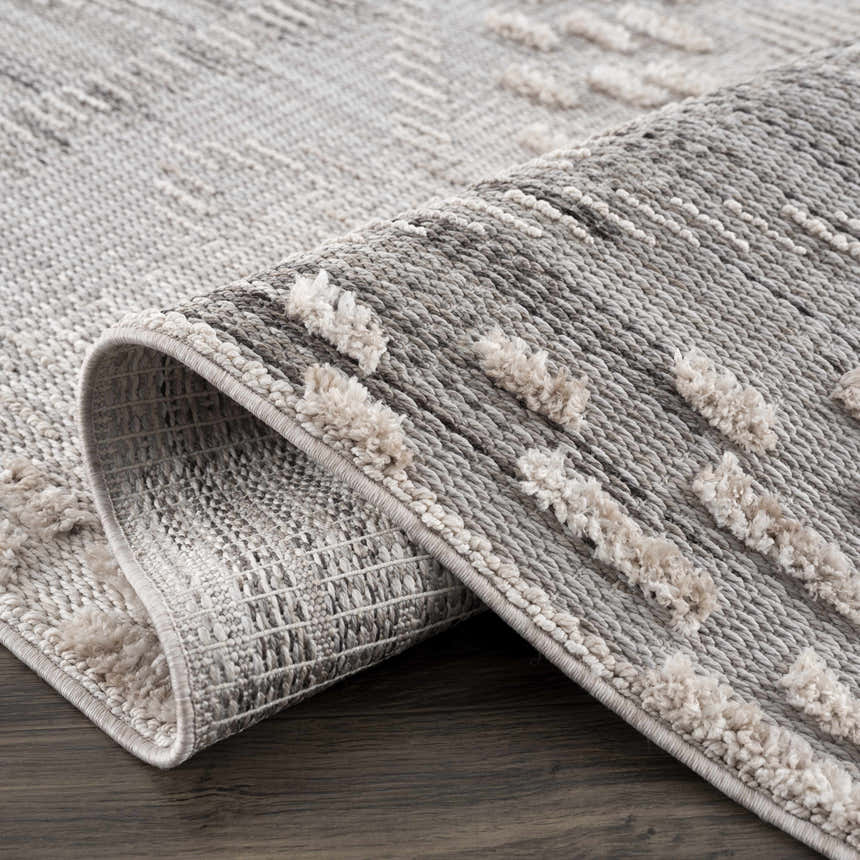 Close-up of the Poydras High-Low Rustic Rug. Charcoal and gray rug with a textured, high-low design. Fold