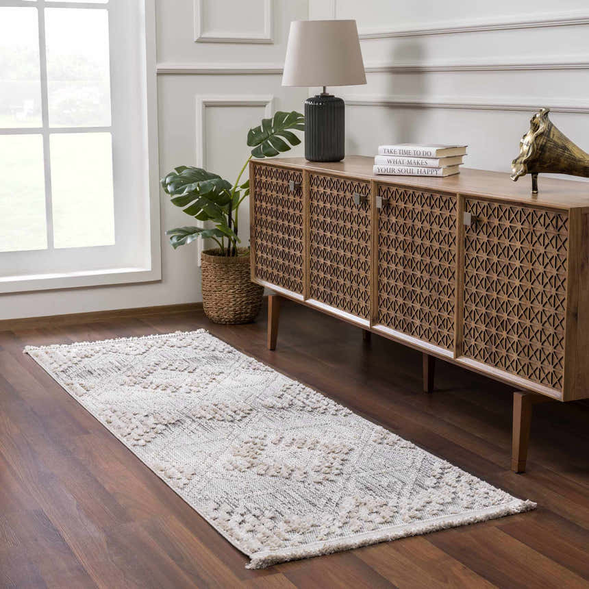 Entryway scene with a gray and beige Poydras High-Low Rustic Rug, wooden console table, lamp, and monstera plant. Roomscene-Runner