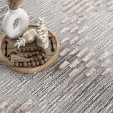 Close-up of the Poydras High-Low Rustic Rug. Charcoal, gray, and beige rug with a textured, geometric stripe pattern. Styleshot