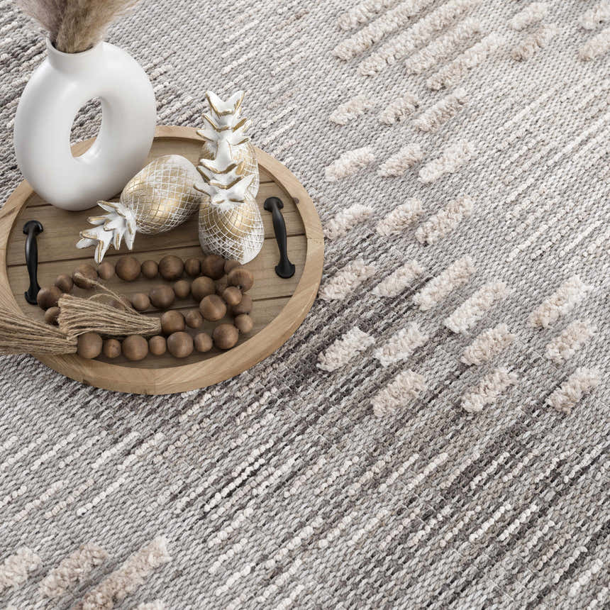 Close-up of the Poydras High-Low Rustic Rug. Charcoal, gray, and beige rug with a textured, geometric stripe pattern. Styleshot