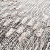 Close-up of the Poydras High-Low Rustic Rug. Features a textured, geometric design in charcoal, gray, and light beige. Texture