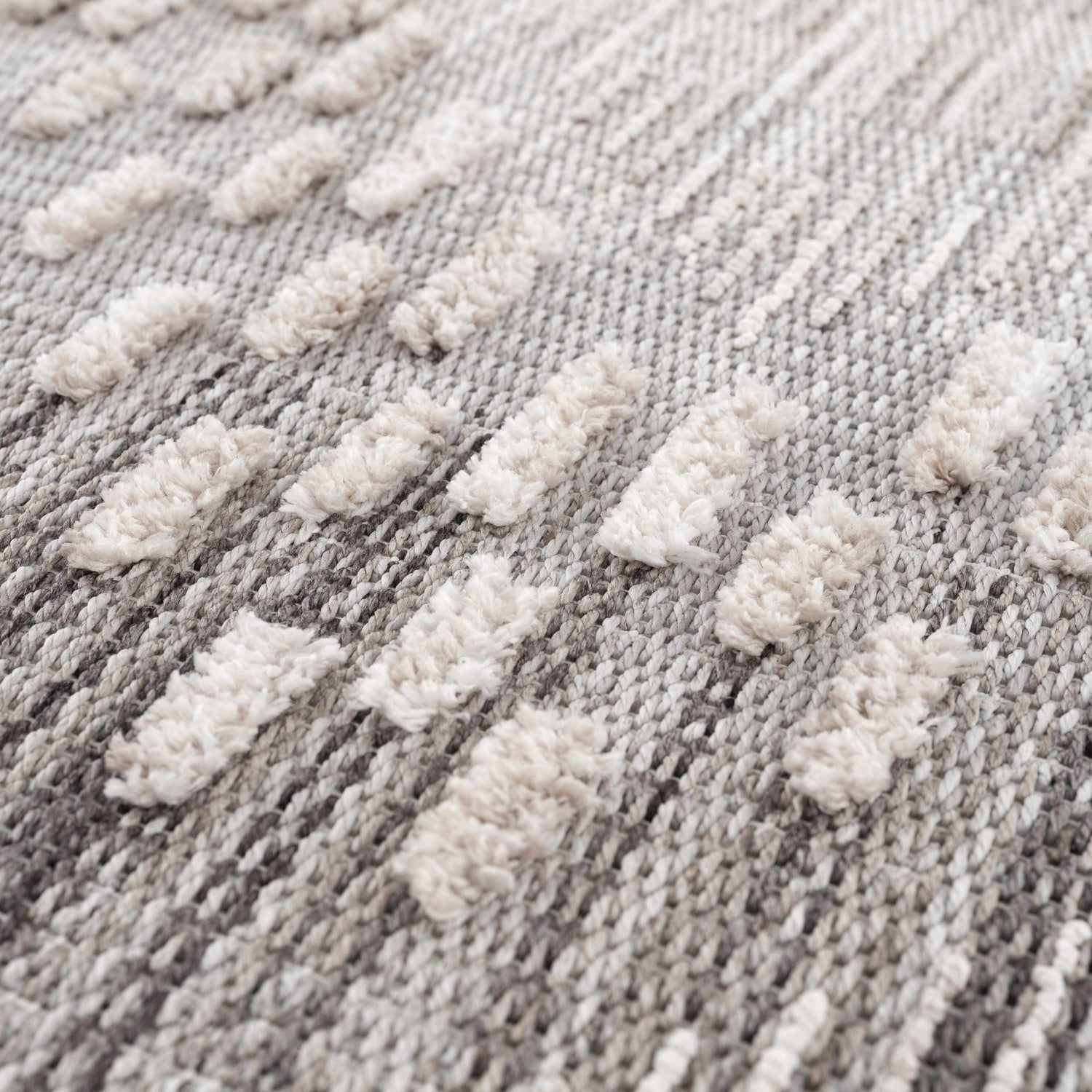 Close-up of the Poydras High-Low Rustic Rug. Features a textured, geometric design in charcoal, gray, and light beige. Texture