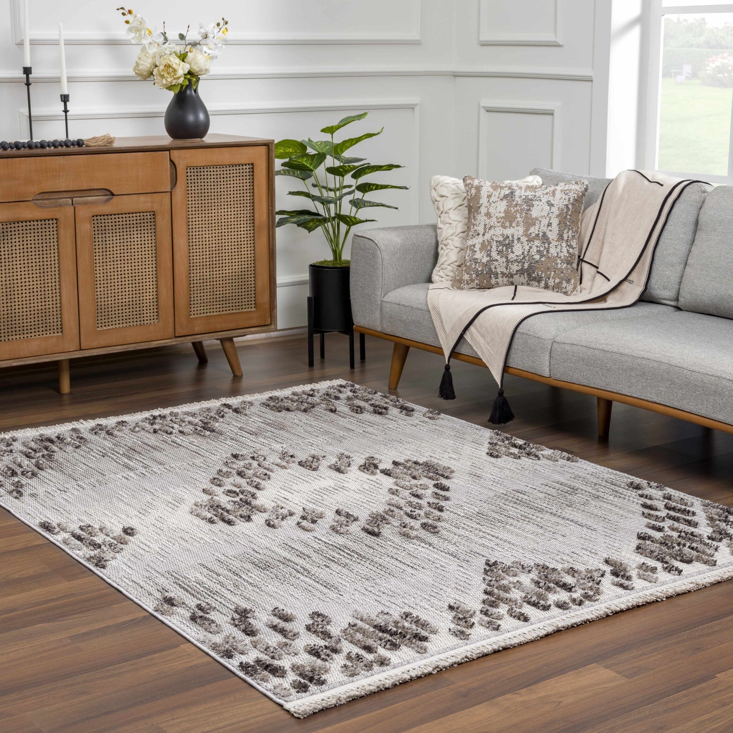 Living room scene with a gray sofa and the geometric Cabarroguis Area Rug in charcoal, cream, and gray. Roomscene-Rectangle