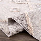 Close-up of the Serkomen High-Low Area Rug showing the geometric pattern and textured, high-pile accents. Neutral color palette. Fold