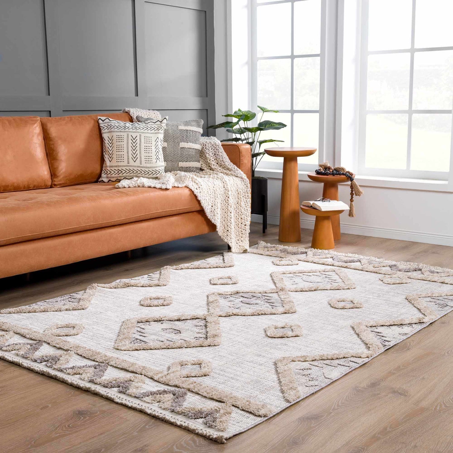 Living room scene with a Serkomen High-Low Area Rug, tan leather sofa, wood side tables, and neutral decor. Roomscene-Rectangle