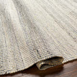 Close-up of the hand woven Abucay Jute Rug, showcasing its charcoal, cream, and light beige colors and textured weave. Fold