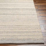 Close-up of the Abucay Jute Rug. Hand woven rug with charcoal, cream, and light beige stripes on a wood floor. Front