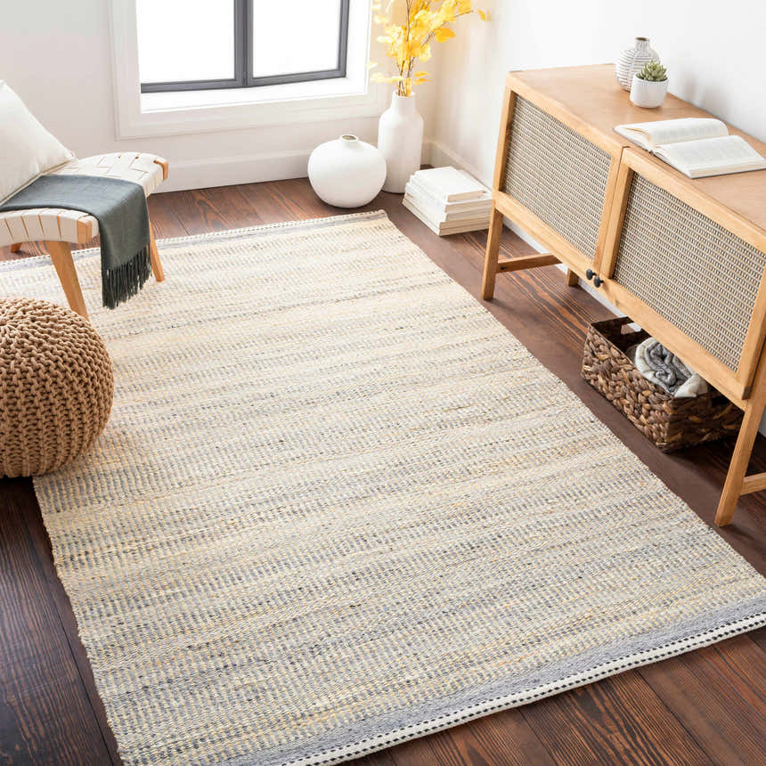 Living room scene with Abucay Jute Rug in cream and charcoal, styled with a wooden cabinet and bench. Roomscene-Rectangle