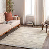 Living room scene with a charcoal and cream Abucay Jute Rug, light beige sofa, wooden side table, and neutral curtains. Roomscene-Rectangle