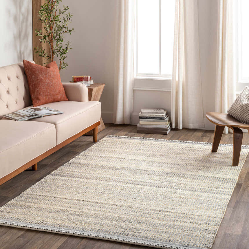 Living room scene with a charcoal and cream Abucay Jute Rug, light beige sofa, wooden side table, and neutral curtains. Roomscene-Rectangle