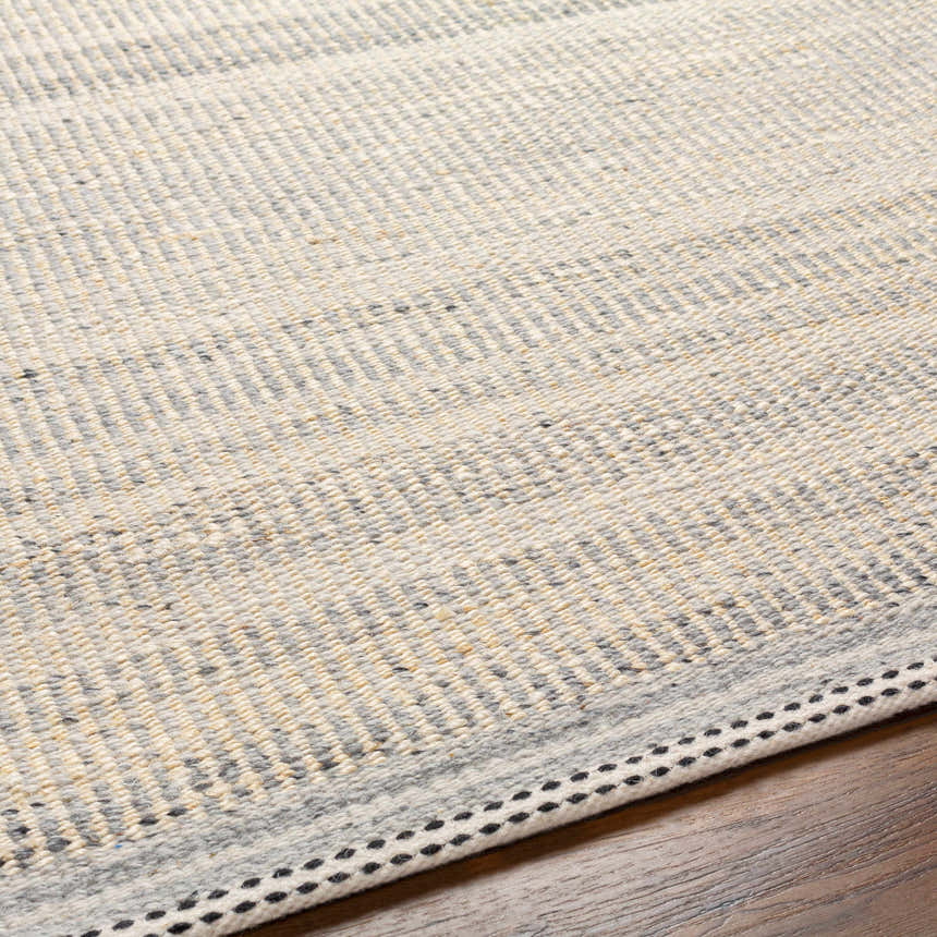 Close-up of the hand woven Abucay Jute Rug. Charcoal, cream, and light beige jute and wool fibers create a textured look. Texture