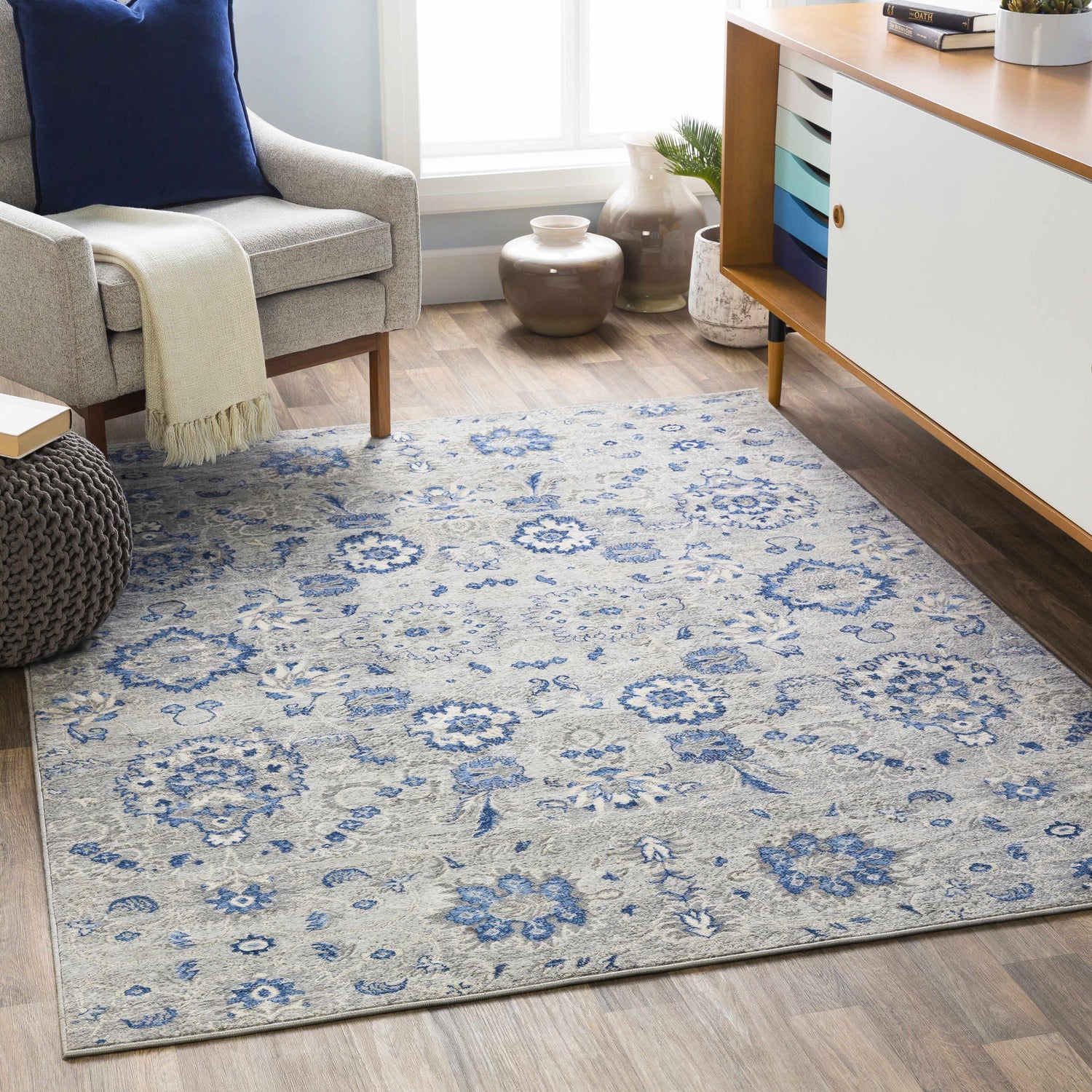 Living room scene with Adairsville Blue Floral Area Carpet, gray armchair, and modern white cabinet. Denim and gray tones create a calming mood. Roomscene-Rectangle