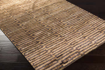 Close-up of the Addieville Area Carpet. Black, brick red, and brown hand-knotted viscose rug with a contemporary geometric pattern. Corner