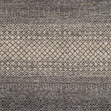 Close-up of the hand-knotted Adlay Area Rug. Black, charcoal, and oatmeal wool rug with a diamond pattern. Swatch