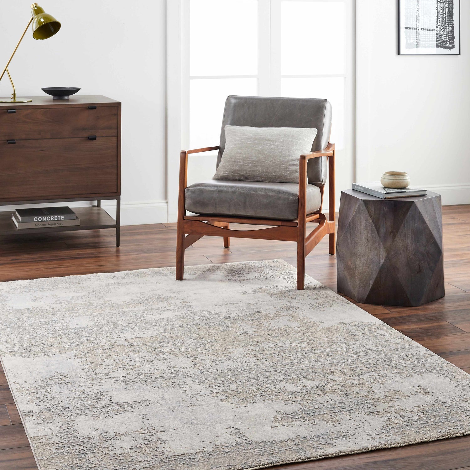 Living room scene with a gray Adwoa Boutique Rug, leather chair, wood side table, and dresser on dark wood floors. Roomscene-Rectangle
